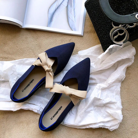 Navy blue shoes with beige bows on a white fabric background